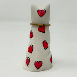 A white resin lucky cat figurine decorated with hand-painted red hearts and a thin gold collar