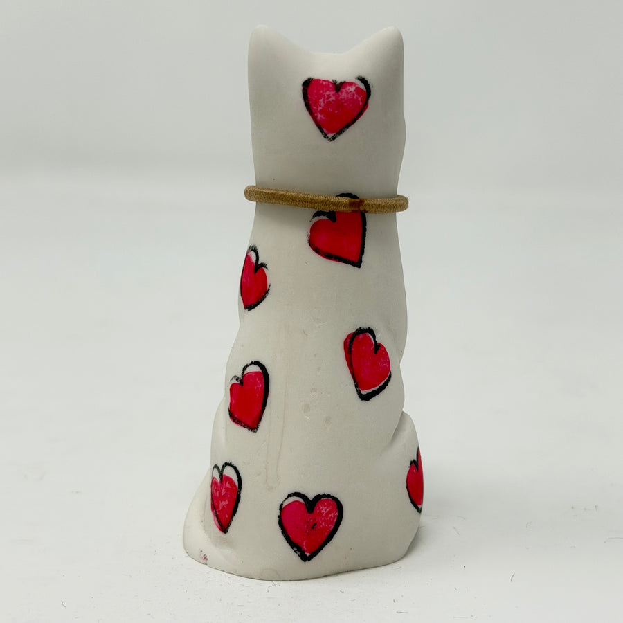 A white resin lucky cat figurine decorated with hand-painted red hearts and a thin gold collar