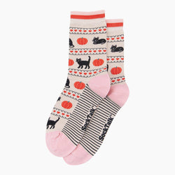A pair of crew socks with a fall-themed pattern featuring black cats, orange pumpkins, and red hearts on a cream background