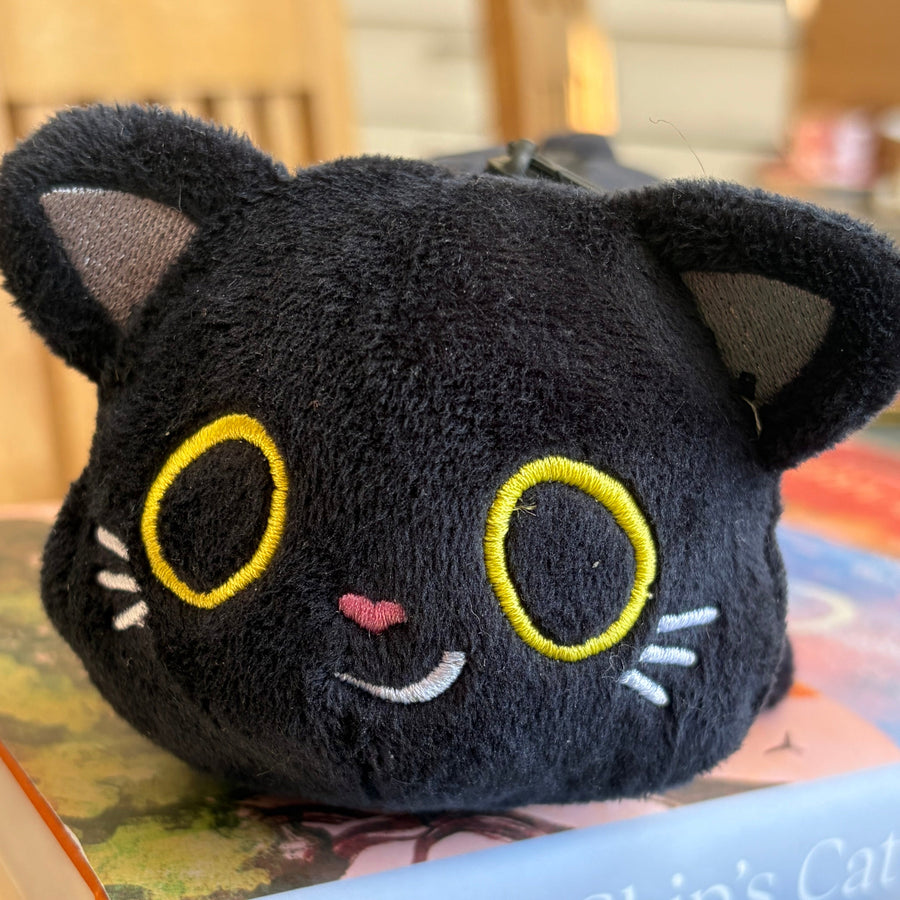 A black plush cat head pouch or bag with embroidered yellow eyes, white whiskers, and a small pink nose