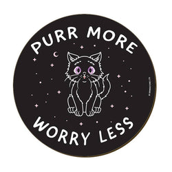 A round black coaster featuring a white line-art illustration of a cat with purple eyes, surrounded by stars and the text 'PURR MORE WORRY LESS'.