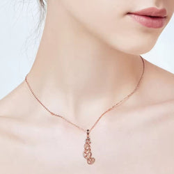 A close-up of a model's neck and lower face wearing a delicate rose gold chain with a matching stylised pendant