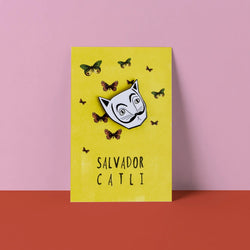 White Cat Head in the style of Salvador Dali with black moustache. Ona card labelled Salvator Catli