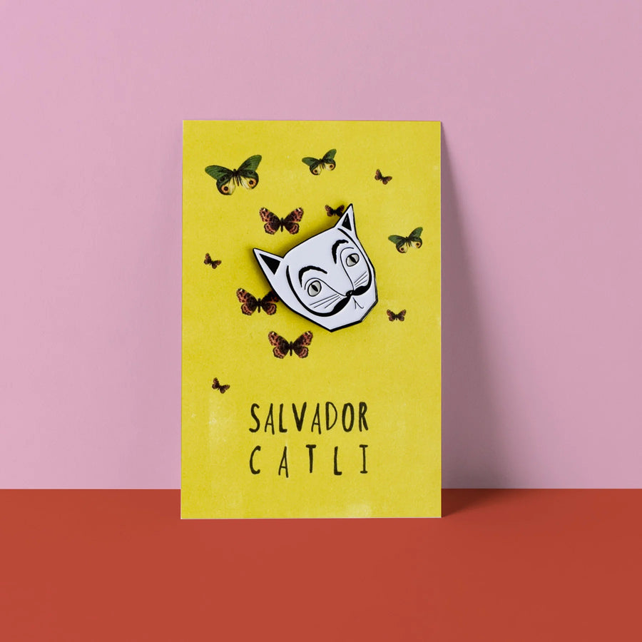White Cat Head in the style of Salvador Dali with black moustache. Ona card labelled Salvator Catli