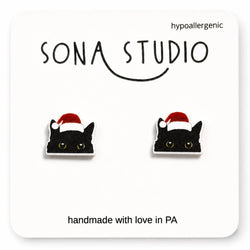 Black cat earrings with Santa hats on a Sona Studio branded card.