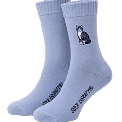 A pair of light blue crew socks with a small black and white cat graphic on the front sock. 