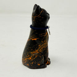 A black lucky cat resin figurine with orange marbled splatters, wearing a dark blue collar with a small silver charm