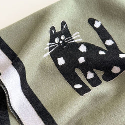 Black and white cat design on a green fabric background