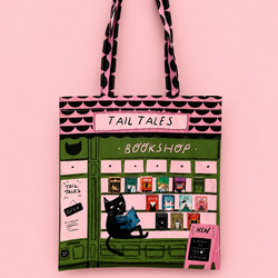 A tote bag featuring a whimsical illustration of a bookshop storefront with the words 'TAIL TALES BOOKSHOP' and a black cat sitting in front