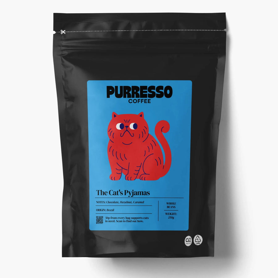 A black stand-up coffee bag with a blue label featuring a red illustrated cat and the text 'PURRESSO COFFEE' and 'The Cat's Pajamas'
