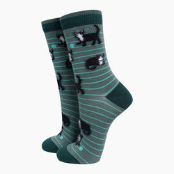 A pair of crew socks in dark green with thin teal horizontal stripes and a pattern of small black-and-white kitten 