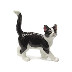 A glossy black and white ceramic figurine of a walking cat, shown against a plain white background.