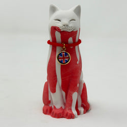 A white resin lucky cat figurine with red splattered across its body, wearing a red collar with a Union Jack charm