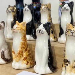 Collection of ceramic Winstanley lucky cat figurines with various patterns on a wooden surface.