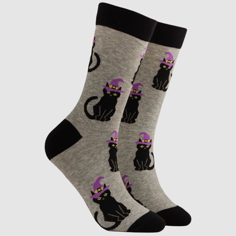 A pair of crew socks in heather grey featuring a repeating pattern of black cats wearing purple witch hats