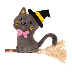 A plush grey cat toy wearing a black and yellow witch hat and a pink bow tie, sitting on a straw broomstick against a plain white background.