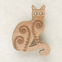A wooden brooch in the shape of a cat with etched patterns