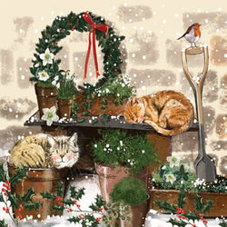 A coaster featuring a festive illustration of cats in potted plants, a wreath, and a shovel in a snowy scene.