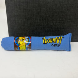 A blue fabric catnip toy with yellow embroidered 'Yeoww! Catnip' text, shown on a white surface with a dark textured box in the background.