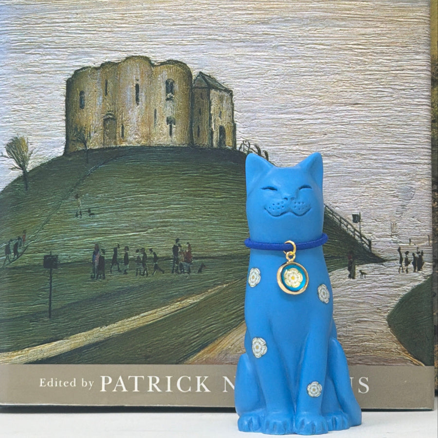 Yorkshire Rose blue cat with blue collar and yorkshire rose charm displayed in front of a book with Cliffords Tower York on the cover