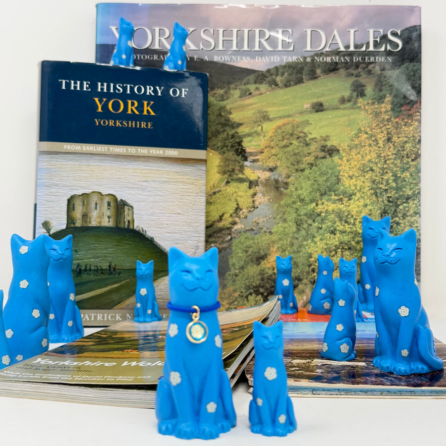 Cat and kitten blue ornaments decorated with white roses with blue collar with round white rose charm, displayed with books about Yorkshire