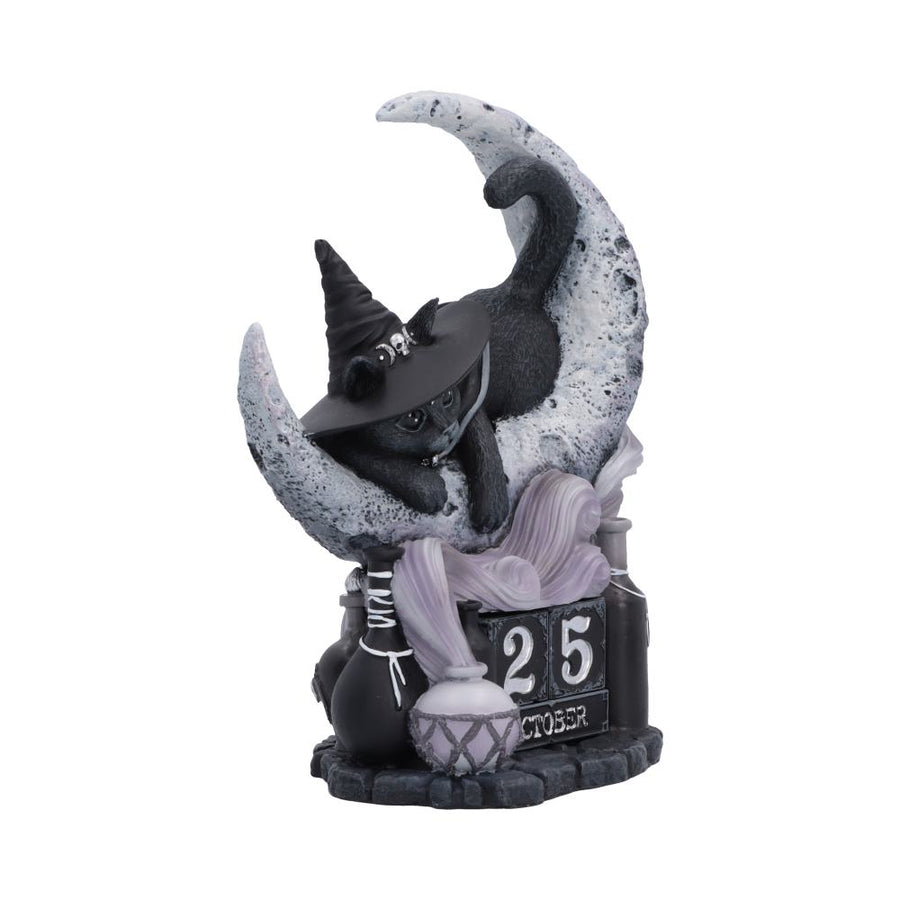 Decorative figurine of a cat in a witch hat on a moon with '25 October' text. The whole forming a perpetual calendar - side view