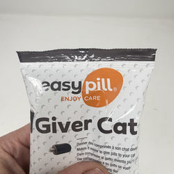 A hand holding a white bag of Easy Pill Giver Cat pills against a plain light background. The packaging is white with a black top seal, black text, and an orange circular logo that reads 'easy pill'.