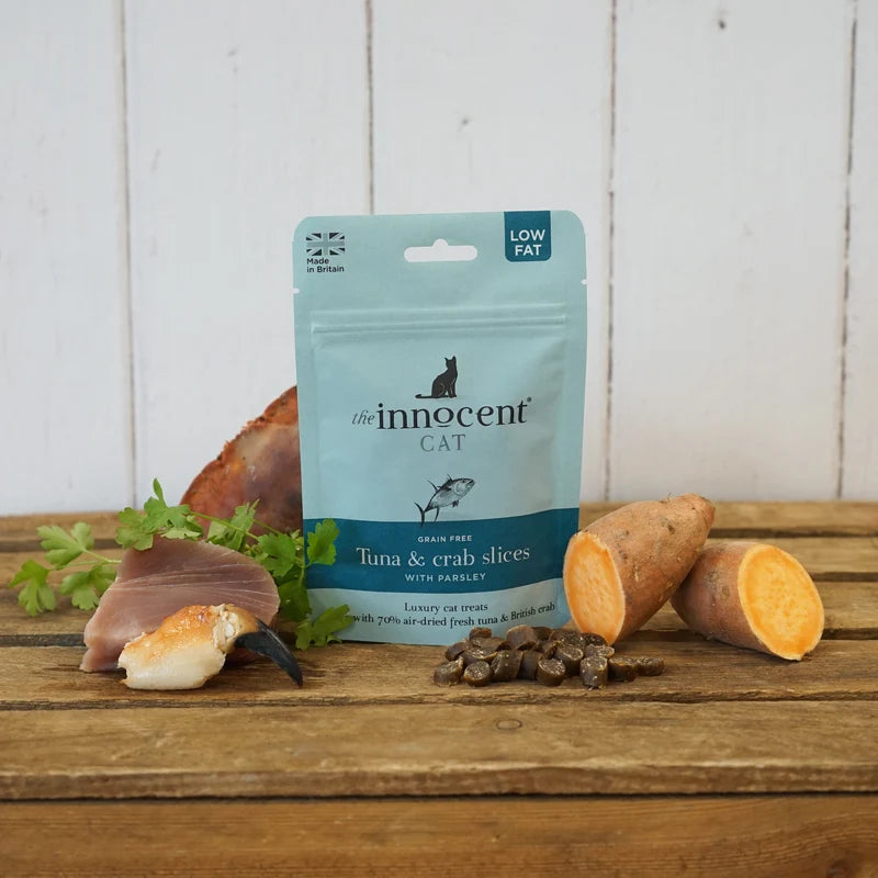 Pack shot of innocent cat tuna and crab treats  on a wooden surface with scattered treats