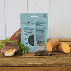 Reverse of Pack shot of innocent cat tuna and crab treats  on a wooden surface with scattered treats