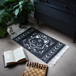 Lifestyle setting for a Black rug with white tassels with mystical white cat motif featuring pentagram stars and moons
